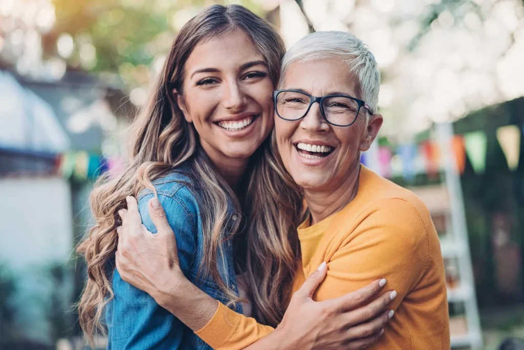 a woman and an older one hugging each other while laughing