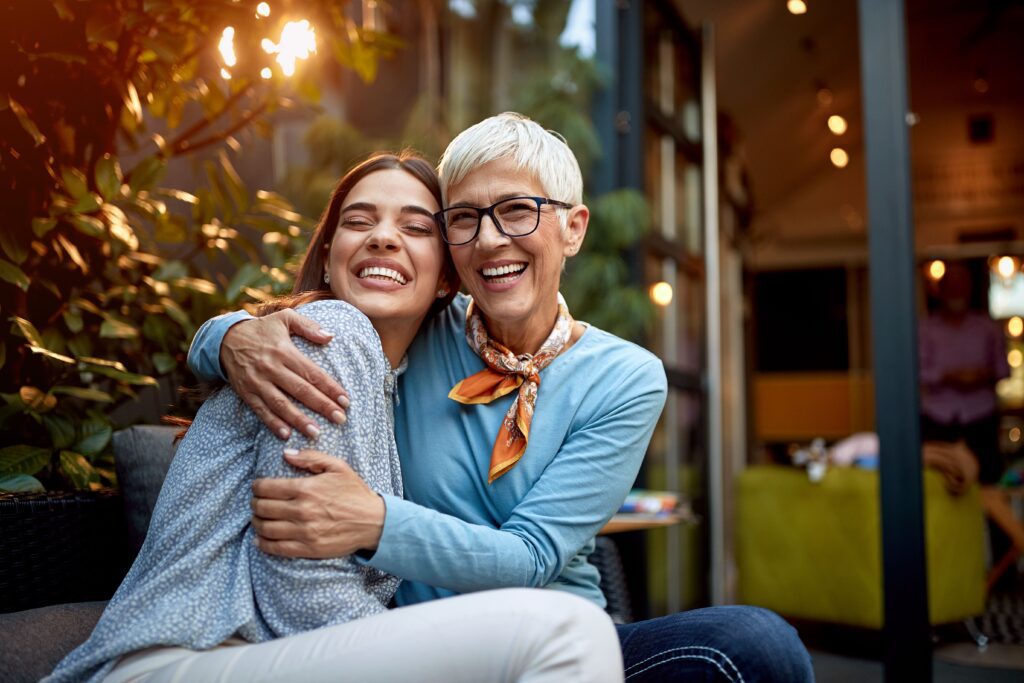 a woman and an older one hugging each other while laughing