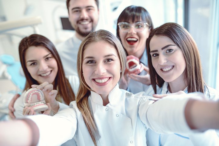 a group of happy dentists and staff taking a selfie